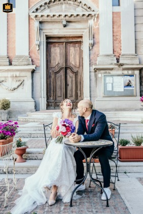 Bride and groom waiting for a coffee together at a café in Mercato Saraceno square, Italy, after their wedding.